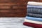 Stack of knitted winter clothes and wool sweaters on wooden background. Copy space for text.