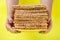 A stack of matzo in the hands of a woman on a yellow background.