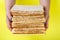 A stack of matzo in the hands of a woman on a yellow background.