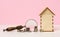 Stack of metallic money and magnifier and wooden house on a pink background. Real estate rental