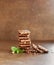 Stack of milk chocolate bar with nuts decorated green mint leaves on a brown surface