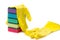 A stack of multicolored sponges and yellow rubber gloves for wet cleaning and dish washing on a white background