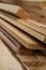 Stack of natural brown uneven rough wooden boards on building site. Industrial timber for carpentry, building