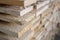 Stack of natural rough wooden boards close-up. Storage of wood in a carpenter`s workshop or at a sawmill