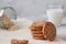 A stack of oatmeal cookies, a glass of milk, cereal on a wooden table and a gray background in a high key