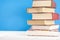 Stack of old books, blue background, free copy space. Antique old hardback books on a wooden shelf on a deck table, unmarked,