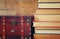 Stack of old books next to antique wooden chest on wooden shelf. vintage filtered