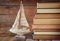 Stack of old books next to decorative sailing boat wooden table. vintage filtered image