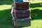 A stack of old fashioned suitcases sit on the grass