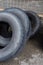 Stack of old used tires of different sizes and types in abandoned scrap yard.