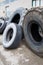 Stack of old used tires of different sizes and types in abandoned scrap yard.