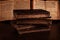 Stack of old worn shabby jewish books in leather binding and open blurred Torah in the background in the dark. Closeup