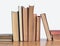 Stack of old yellowed books on a wooden shelf