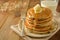 Stack of pancakes with banana slices and honey, on wooden background. Homemade american pancakes, isolated