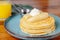 A stack of pancakes with bananas on top of them is served on a blue plate