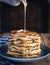 Stack of pancakes with butter and drizzling honey on wooden background