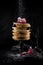 A stack of pancakes decorated with berries and powdered sugar, rustic studio shot