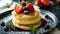 Stack of pancakes with fresh strawberries, blueberries, and syrup