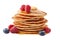 Stack of pancakes with maple syrup and fresh berries on white