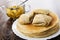 Stack of pancakes, pancakes with apple filling, apples with sugar syrup, spoon in bowl on wooden table