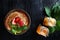 A stack of pancakes with strawberries and mint . Two jars of honey on the table. Photo on a black background. Copy of the space.