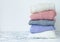 Stack of pastel color clothes. Pile of folded warm sweaters on marble table with copy space