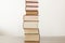 Stack of piled books rest on a wooden table with copy space for your text