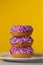 Stack of pink, purple and blue sprinkle covered donuts