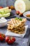 A stack of ready-to-eat zucchini waffles and basil on baking paper and fresh tomatoes on the table. Vegetable dietary vegetarian