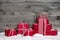 Stack of red Christmas gifts,snow on grey wooden background.