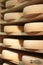 Stack of refining Comte cheese wheels on wood shelves, France