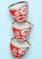 Stack of retro cups with red patterns on a tablecloth.