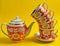 Stack of retro cups and teapot on a yellow background