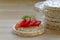 Stack of of rice cakes, one with tomatoes on a wooden board