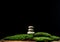 Stack of round stones on green moss, black background. Podium to showcase products, cosmetics and items, advertising