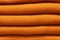 Stack of russet orange woolen knitted sweaters close-up, texture, background