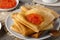 Stack of russian thin pancakes blini with red caviar on an old wooden table. Maslenitsa, traditional Russian blini