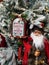 Stack of Santa Claus toys near decorated frosted Christmas Tree