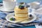 A stack of scotch pancakes with with honey and blueberries on a breakfast table