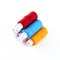Stack of spools of thread bright red, blue and orange on a white isolated background