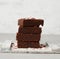 Stack of square baked brownie chocolate cake slices on a white background