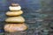 Stack of stones balancing on top in blue water of the river