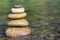 Stack of stones balancing on top in green water of the river