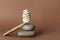 Stack of stones balancing on wooden stick against brown background, space for text. Harmony concept