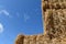 Stack of straw, square bundles straightened on each other. Blue sky.