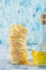 Stack of tagliatelle nests and glass of olive oil on blue background