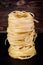 Stack of tagliatelle pasta nests over dark wooden background