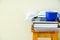 Stack of textbooks notepads workbooks blue cup of hot tea on high wooden stool on white wall background. University college