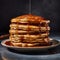 A stack of thick pancakes on a plate with honey dripping over them. Homemade pancakes on a black background.