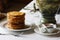 Stack of thin crepes with tea, sour cream, jam and honey. Dish served with a faience samovar on a table covered with a white